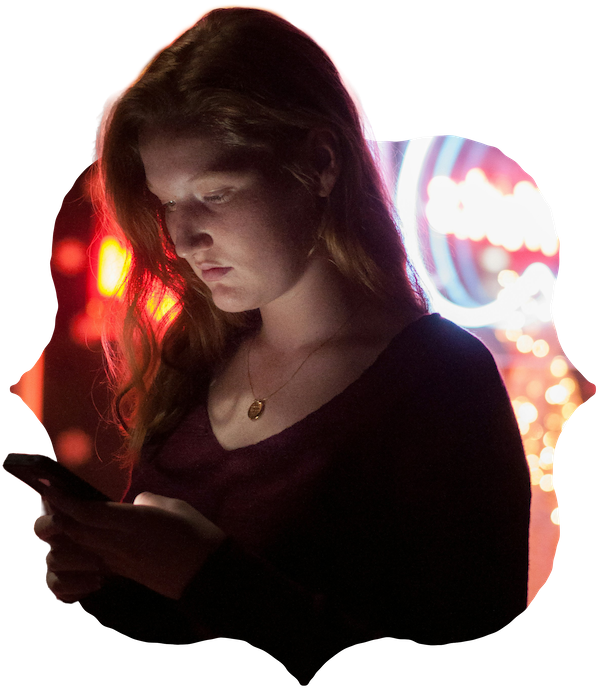 A young woman alone on her phone, lit by blurred coloured lights